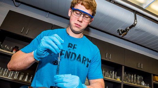 Student prepares test samples in biology lab.